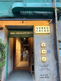 Entrance of Subko Cacao cafe with illuminated sign and narrow hallway leading inside