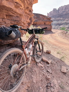 Mountain bike parked on a dirt trail with towering red rock cliffs and desert canyon scenery