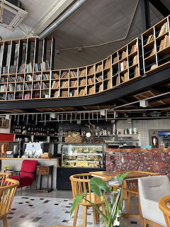 Cafe interior with curved wall of bookshelves, colorful chairs, and display counter