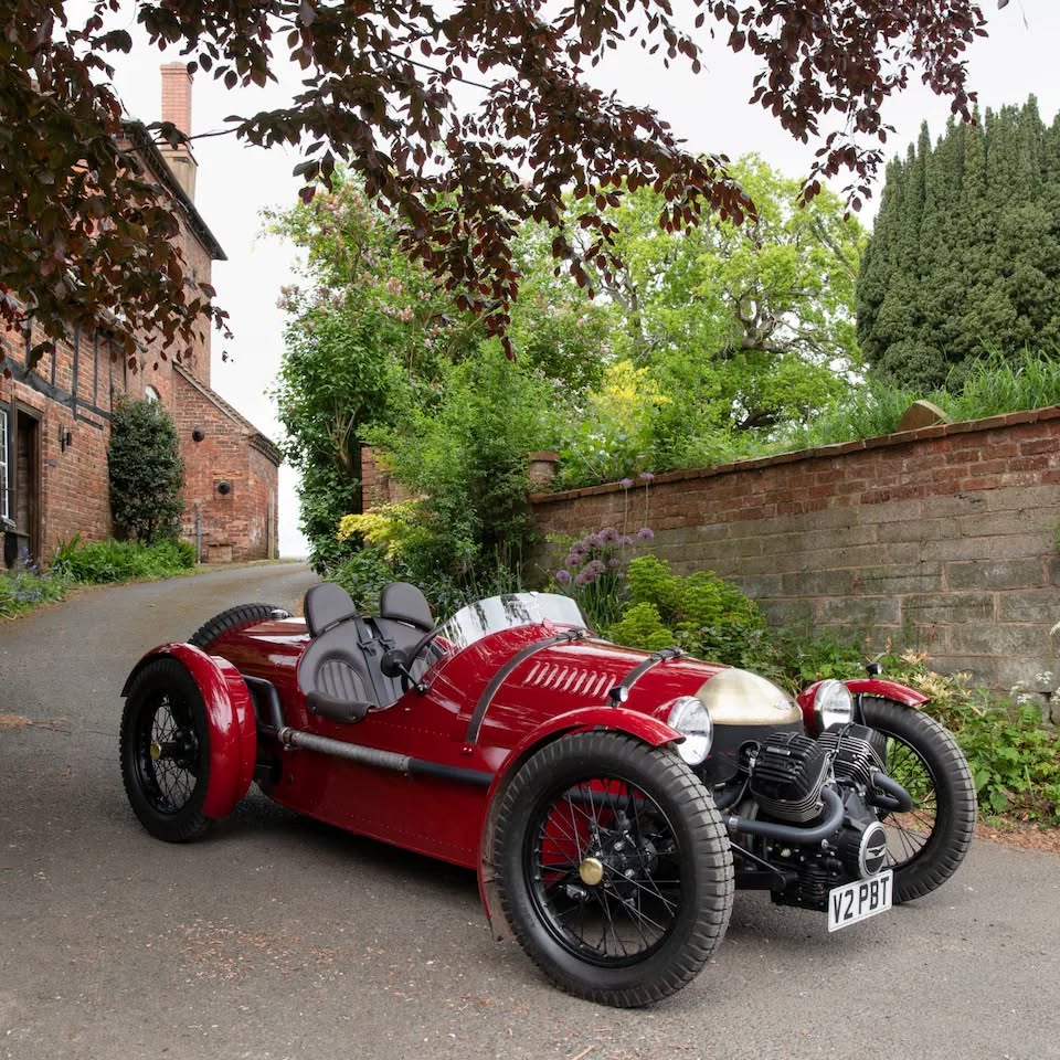 Red vintage Pembleton T24 sports car parked on a narrow lane by brick walls and trees