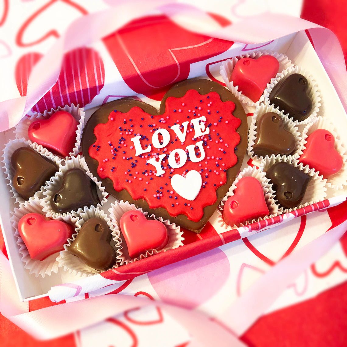 Valentine's chocolate box with heart-shaped candies and 'I LOVE YOU' message on decorative background