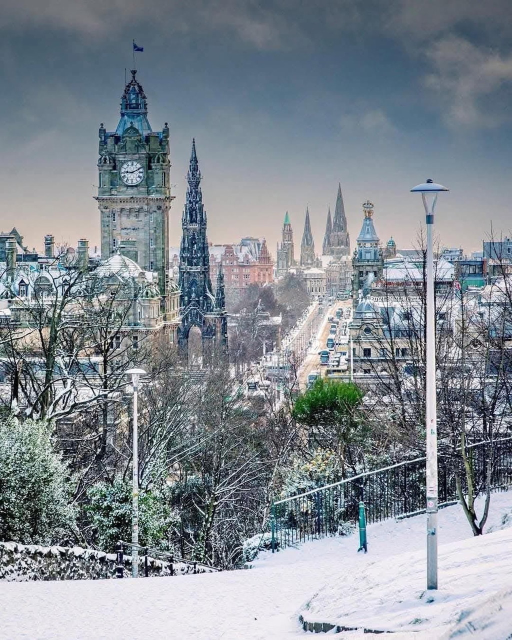 Snowy Edinburgh cityscape with prominent clock tower and historic architecture under winter sky