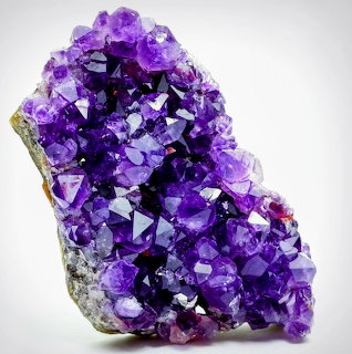 Purple amethyst crystal cluster with faceted quartz points on a light background