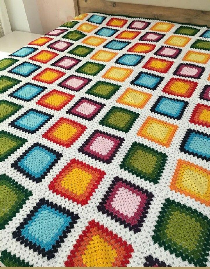 Colorful crocheted granny square blanket spread across a bed