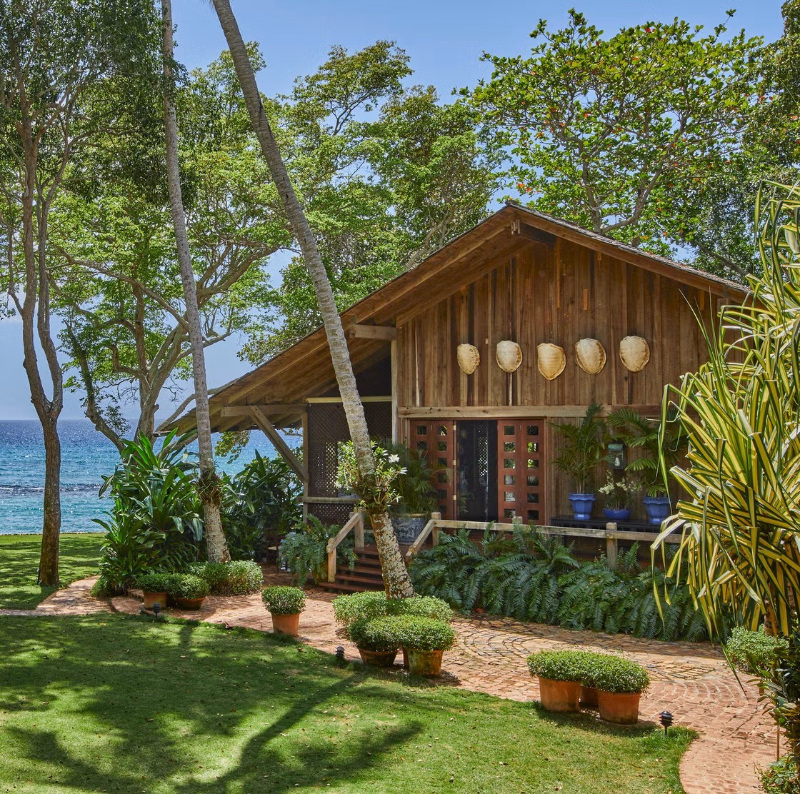 Wooden beach cabin surrounded by palm trees and tropical plants with ocean view