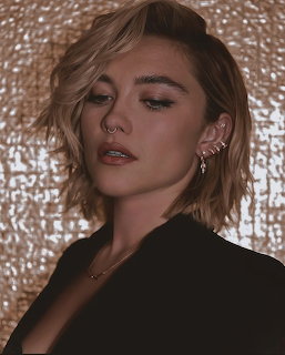 Florence Pugh portrait with short blonde hair, ear cuffs, and black blazer against gold background