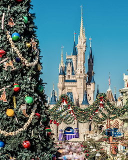 Cinderella Castle with Christmas decorations and a decorated tree in front against a blue sky