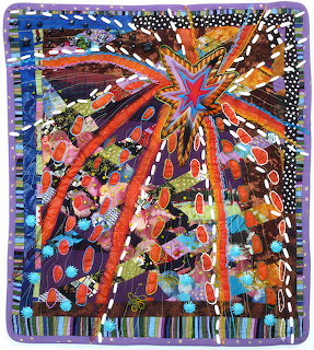 Colorful miniature art quilt with radiating starburst design in orange, blue, purple and multicolored fabric strips with beading