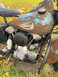 Rusty vintage Harley Knucklehead motorcycle engine with turquoise tank outdoors on fall leaves