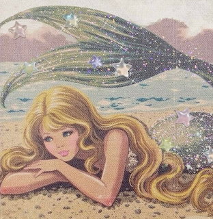 Blonde mermaid lying on a sandy shore with a sparkling tail and sea behind her
