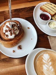 Cinnamon roll, latte art coffee, and toast with jam on a wooden table