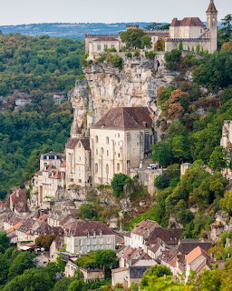 Medieval village of Rocamadour with stone buildings built into a steep cliff surrounded by trees