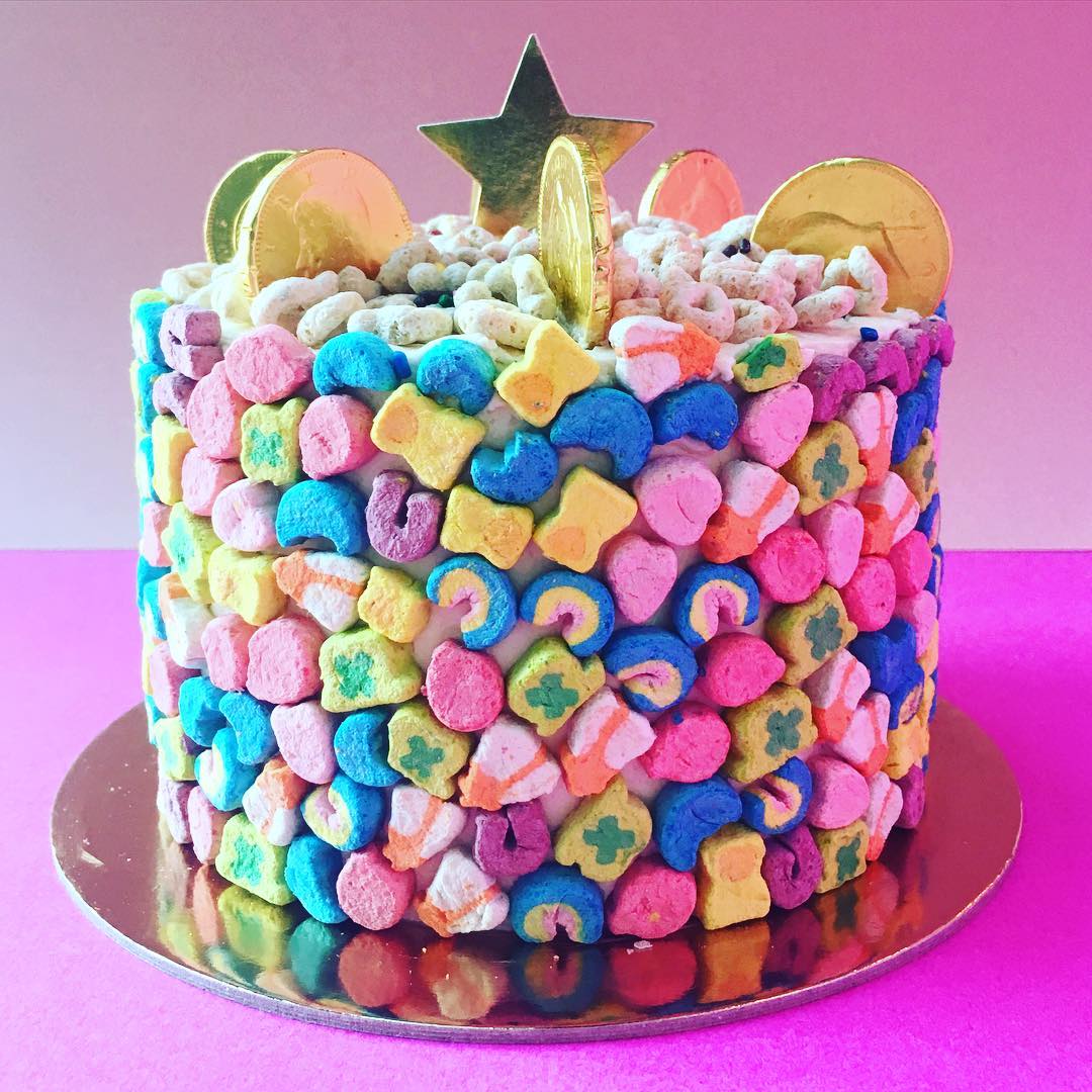Round cake covered in colorful Lucky Charms marshmallows with rainbow and gold coin decorations