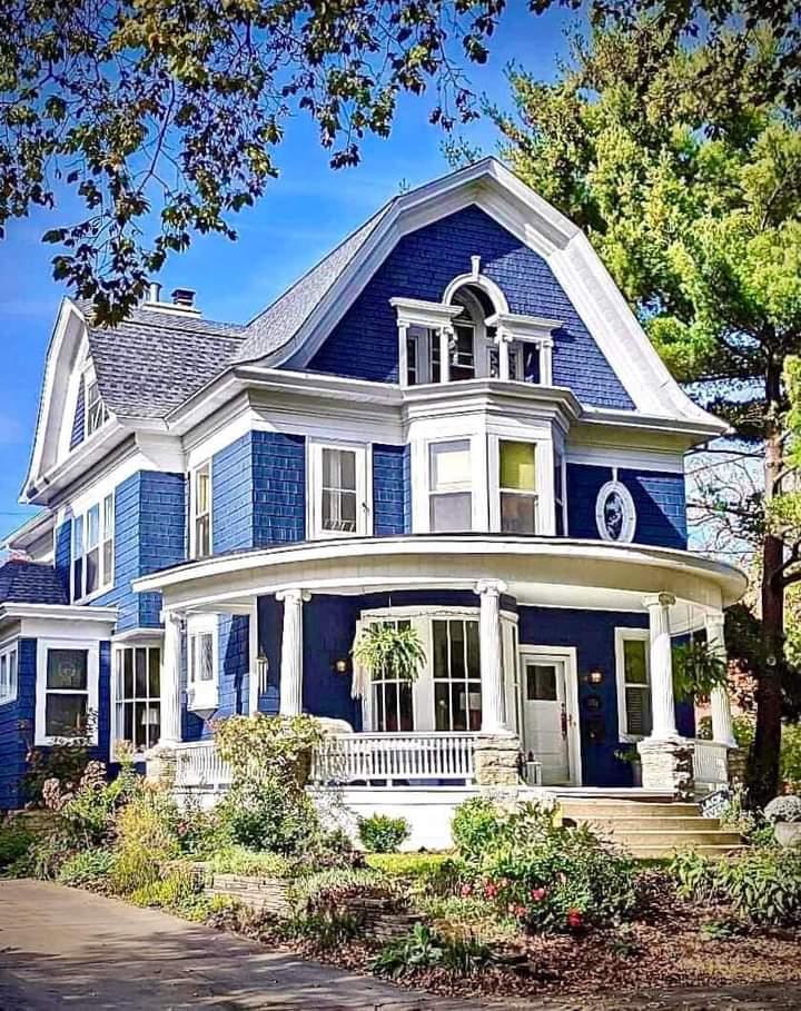 Blue Victorian house with white trim, wraparound porch, and garden in front yard