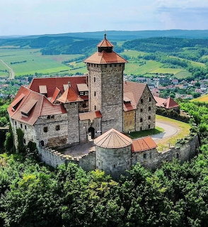 Aerial view of medieval Veste Wachsenburg castle with tower and red roofs surrounded by green landscape