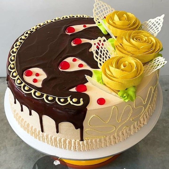 Round decorated cake with chocolate drip icing and yellow rose frosting flowers
