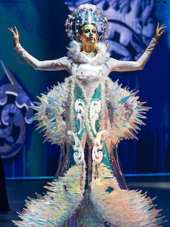 Performer in elaborateridescent spiked fantasy costume with feathered headdress on stage