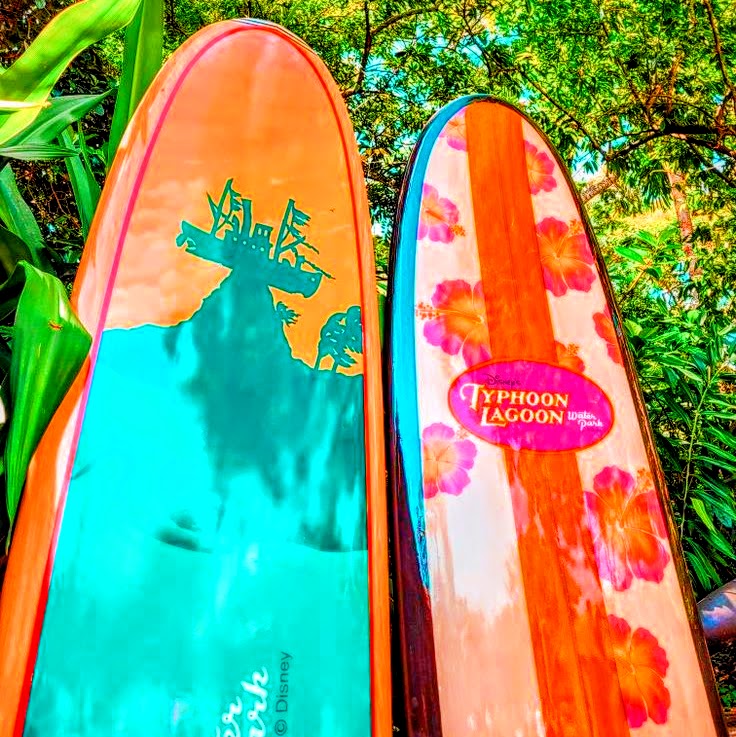 Two colorful surfboards standing among tropical plants and trees