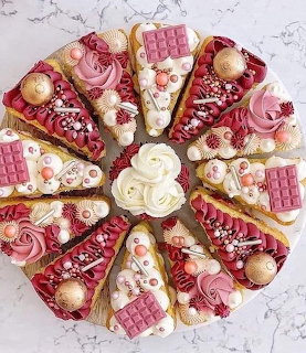 Pink decorated cake slices arranged in circular pattern with berries and chocolate toppings