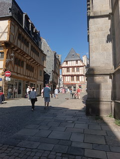 Sunny street with half-timbered medieval buildings and pedestrians in a French town