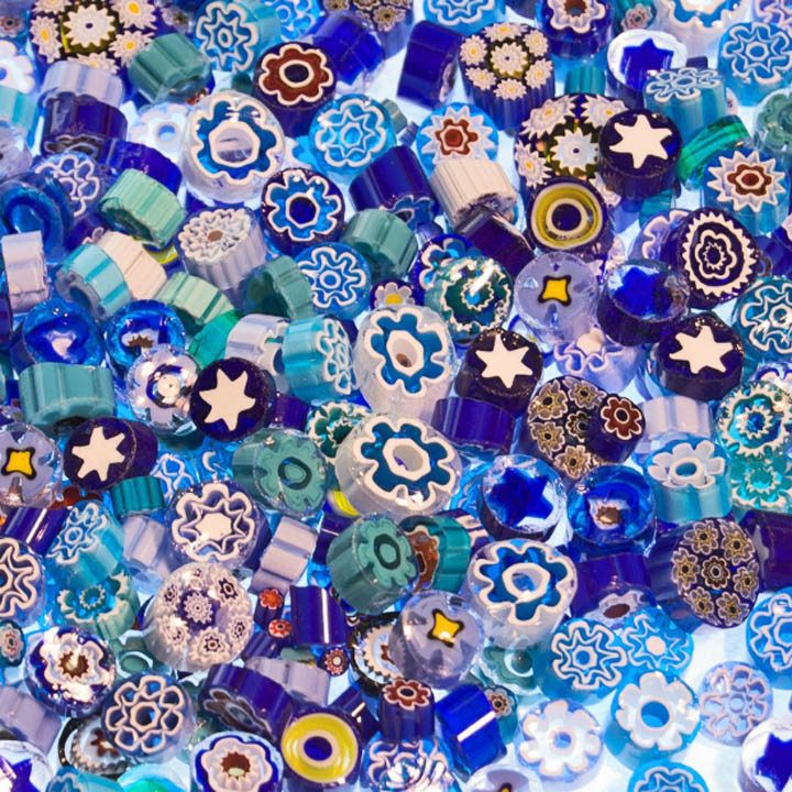 Dense arrangement of blue and turquoise glass mosaic beads with floral patterns