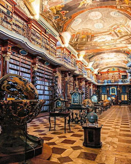 Baroque Clementinum Library in Prague with painted ceiling, bookshelves, globes, and patterned floor