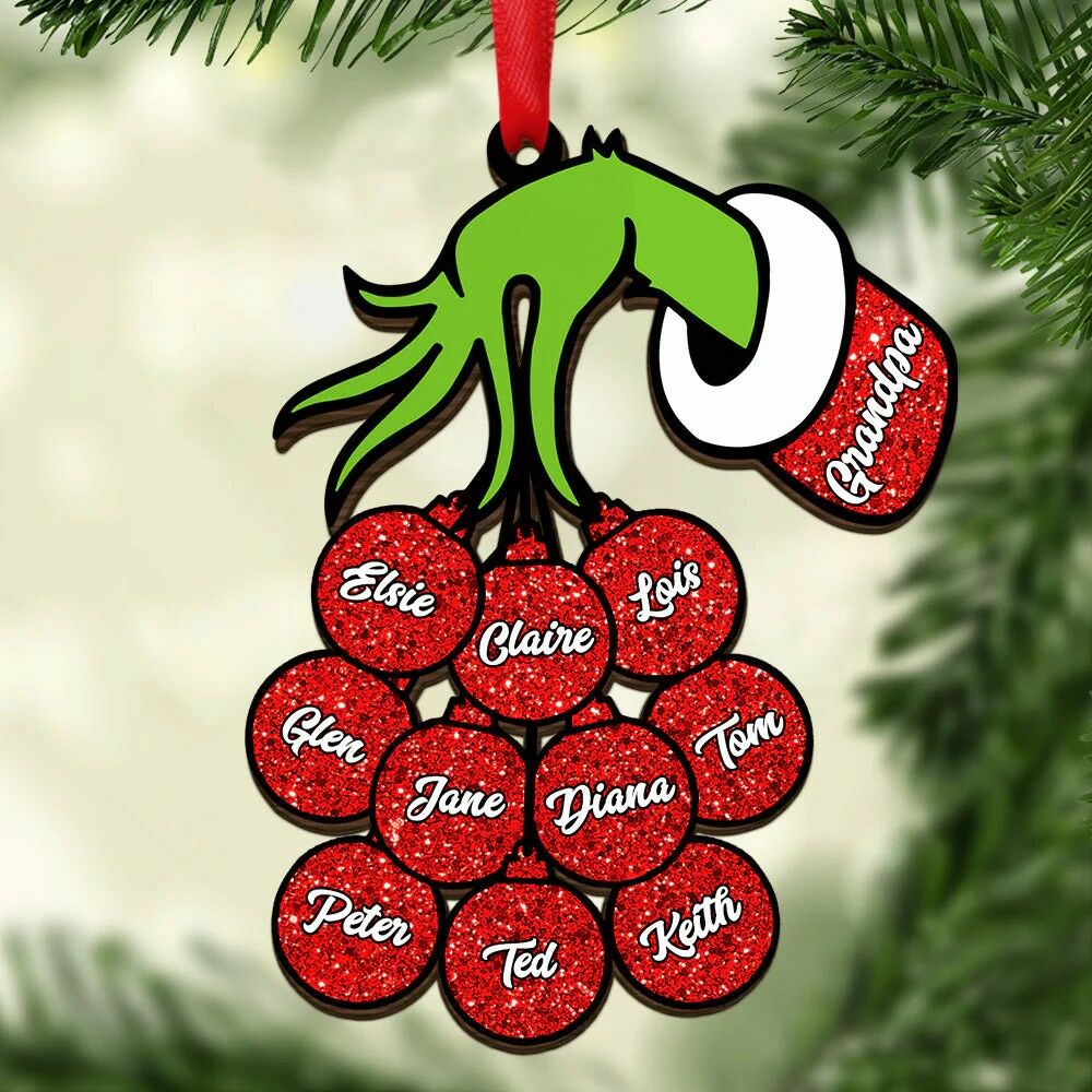 Green Grinch-style hand ornament holding red glitter name circles on a Christmas tree