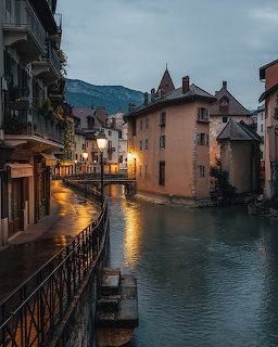 Old town canal in Annecy France at dusk with glowing lamps and medieval buildings reflecting in water