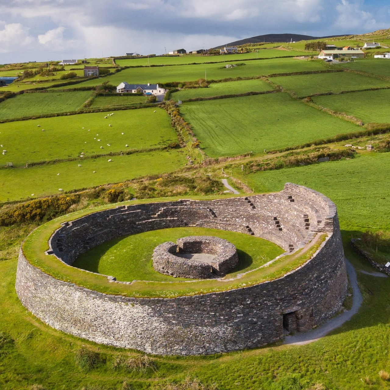 Aerial view of circular stone fort in green Irish countryside with divided farm fields