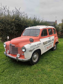Vintage red and white Renault R2093 vehicle parked on grass near a hedge