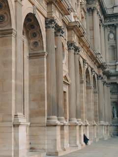 Ornate stone columns and arches along a grand historic building corridor
