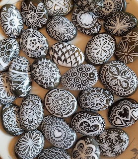 Collection of black and white hand-painted decorative pebbles with mandala and zentangle patterns