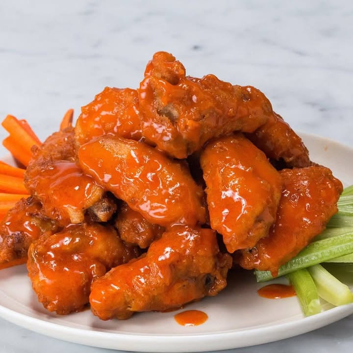 Plate of buffalo chicken wings with celery and carrot sticks