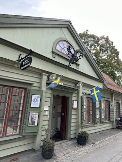 Green wooden shop building with Swedish flag and decorative signs in Sigtuna, Sweden