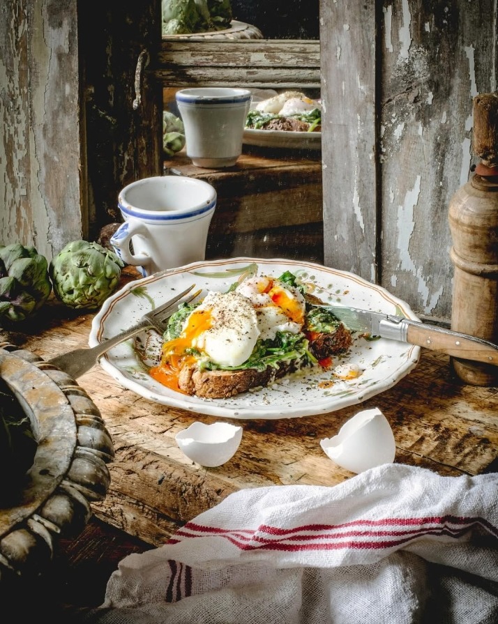 Plate with poached eggs and avocado toast on a rustic wooden table with vintage kitchen decor