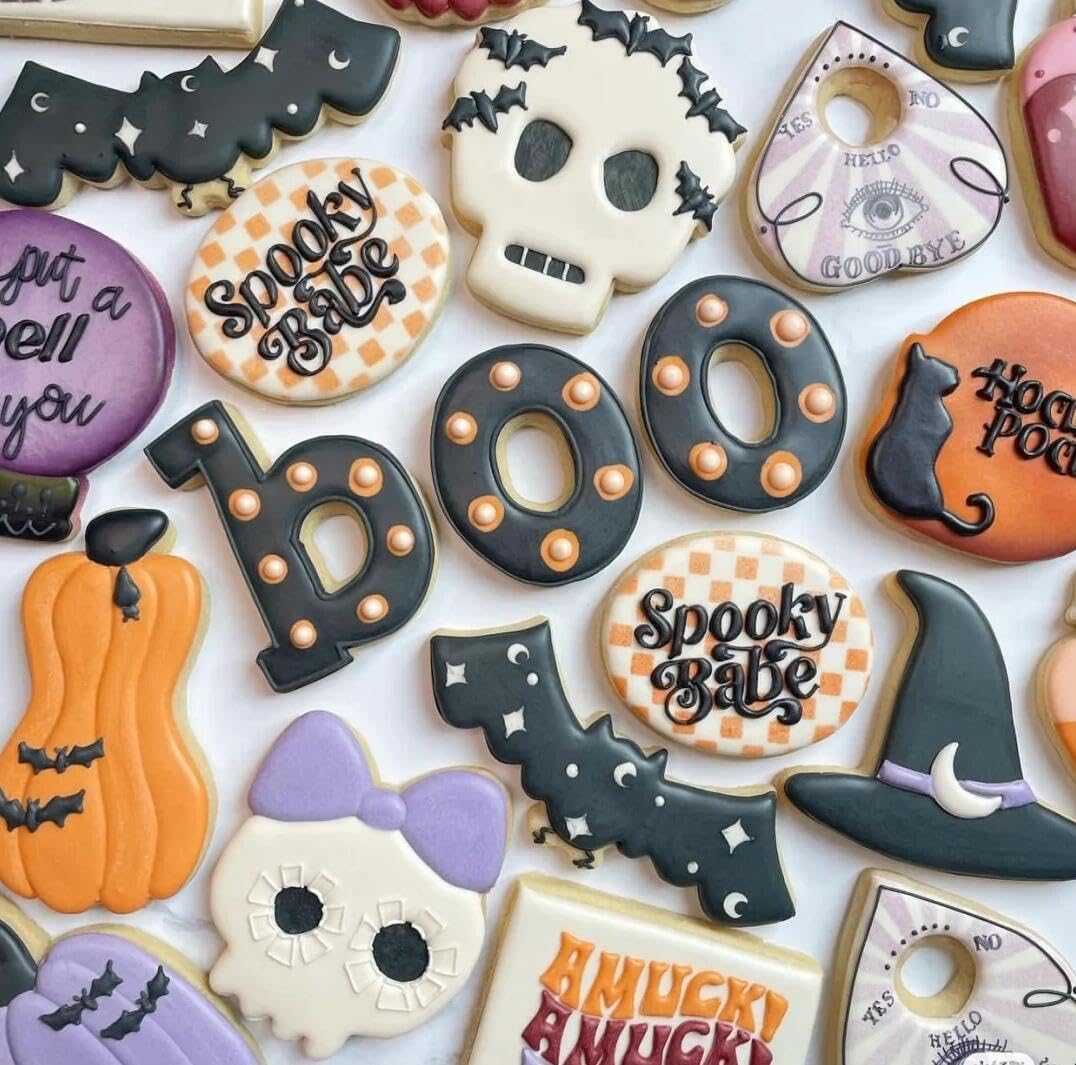 Assorted decorated Halloween cookies including bats, pumpkins, skulls, hats, and boo letters on white