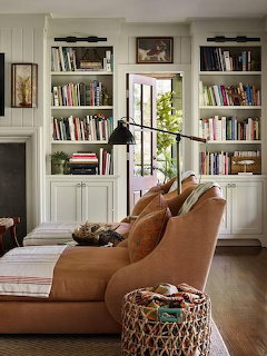 Cozy living room with brown chaise lounge, built-in bookshelves, window seat, and woven basket