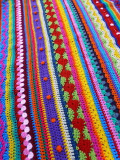 Close-up of a colorful crocheted fabric with striped rows and textured stitch patterns
