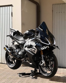 Black Aprilia sport motorcycle parked on a stand outside a building