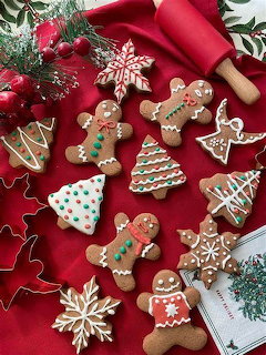Gingerbread men and decorated Christmas cookies on red fabric with pine branches and ornaments