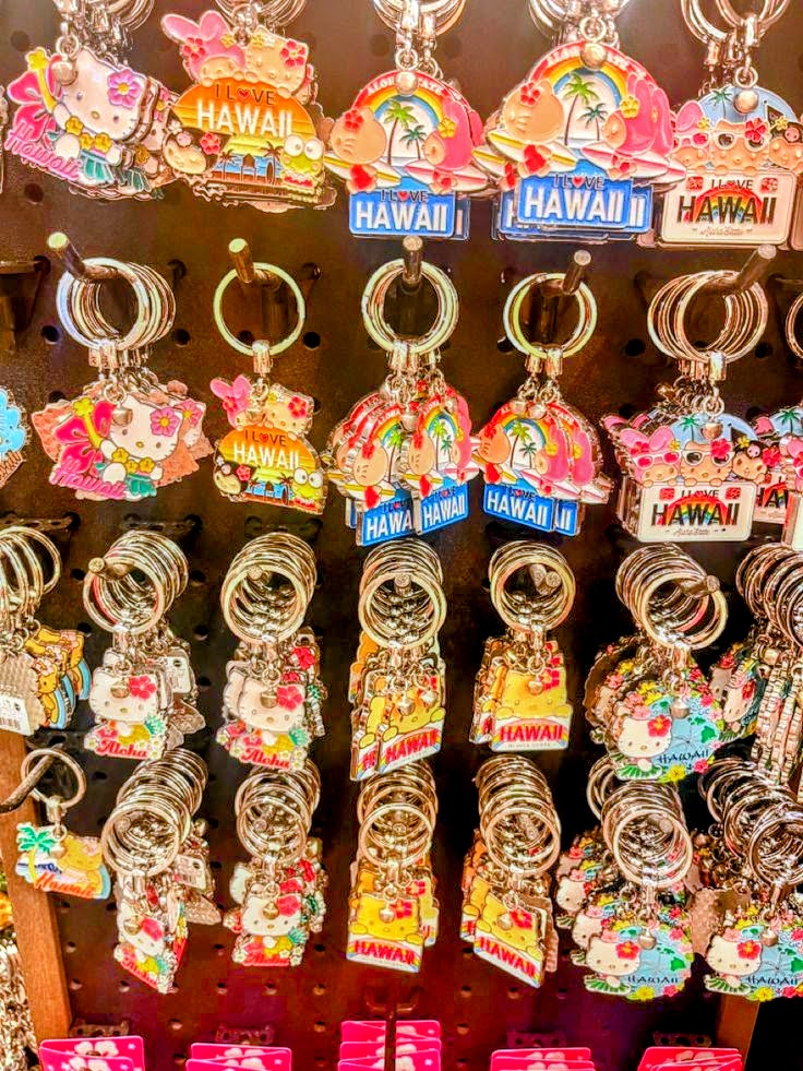Colorful Hawaii souvenir keychains with Hello Kitty and tropical designs hanging in a shop display