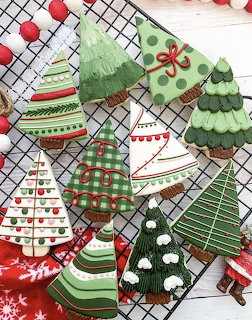 Festive Christmas tree-shaped sugar cookies decorated with green, red, and white icing in various holiday patterns