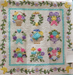 Quilted wall hanging with Easter baskets and flowers in pastel colors, bordered by floral vine pattern