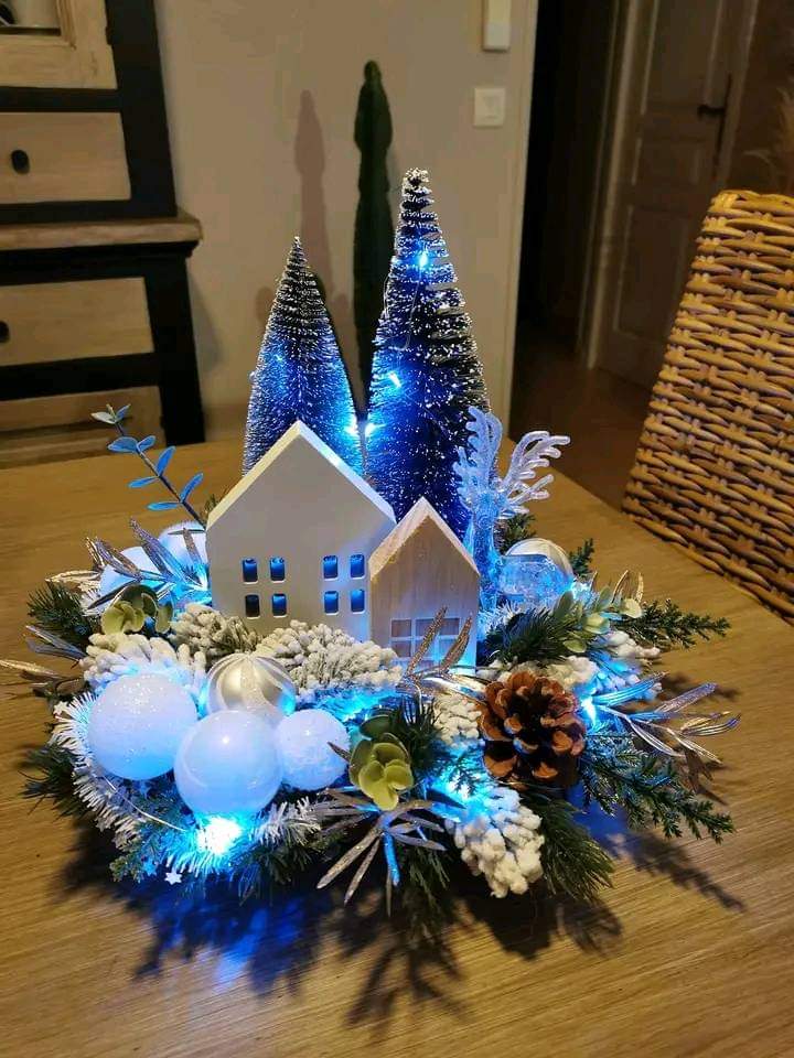 Christmas centerpiece with white ceramic houses, blue LED bottle brush trees, pinecones, and snowy foliage