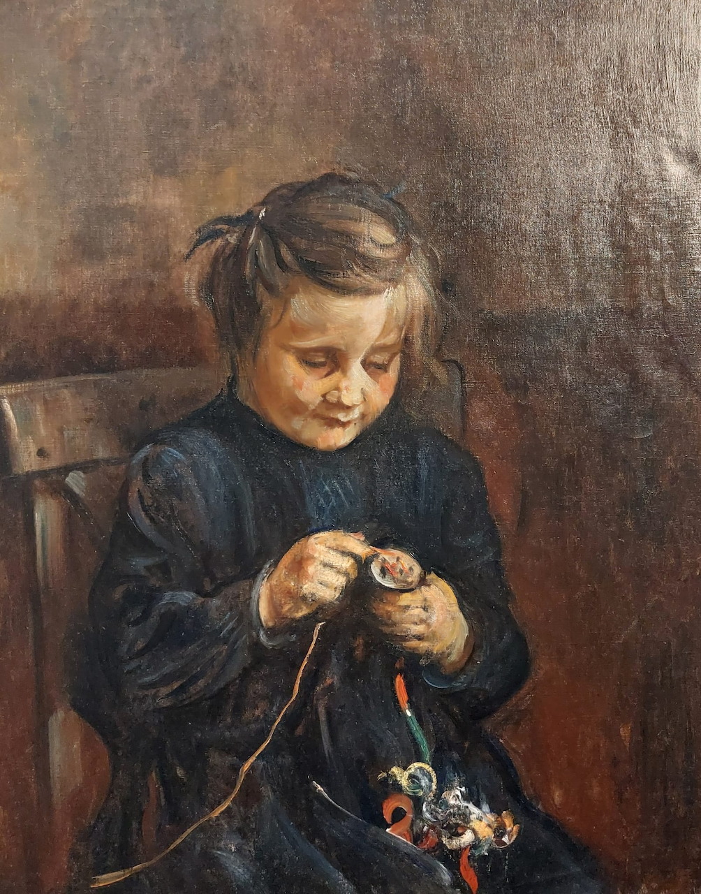 Oil painting of a young child in a dark dress focused on knitting with a warm brown background