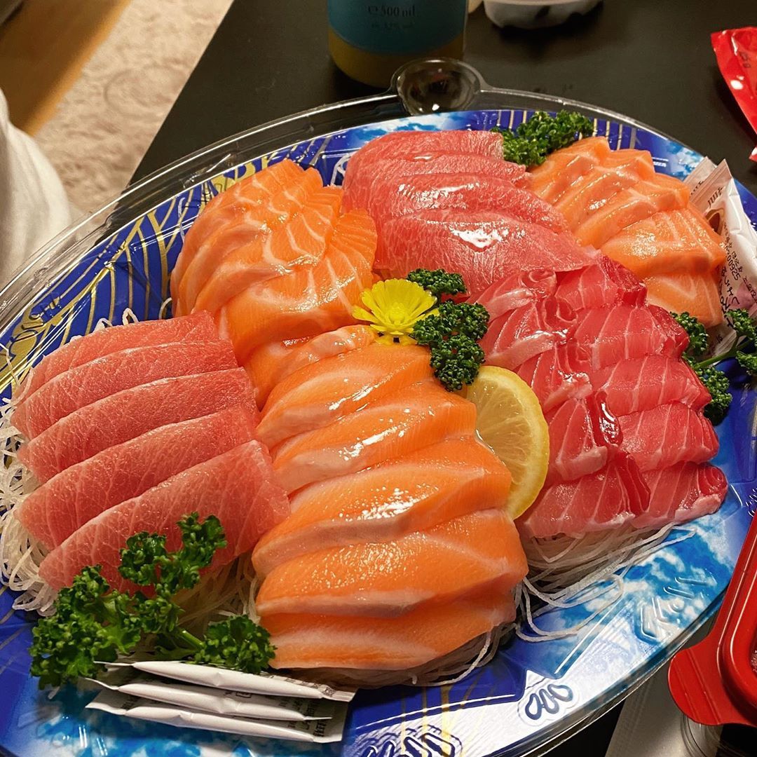 Salmon and tuna sashimi platter on a blue tray with lemon and parsley garnish