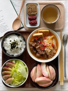 Korean meal tray with rice bowl, soup, kimchi, side dishes and tea cup arranged on table