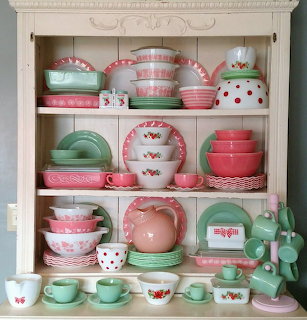 Pink and green vintage dishes displayed in white cabinet shelves