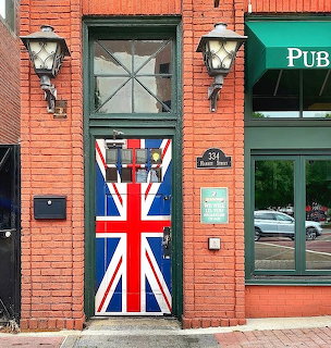 Red brick building entrance with door painted as British Union Jack flag, vintage lanterns on sides