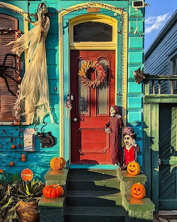 Turquoise house door with Halloween decorations, pumpkins, wreath, and fall decor on steps